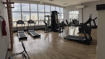 Un gimnasio espacioso con cintas de correr, máquinas de pesas y un amplio ventanal con vistas a la ciudad.