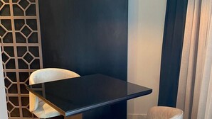 Un comedor moderno con una mesa oscura, dos sillas blancas y una lámpara colgante.
