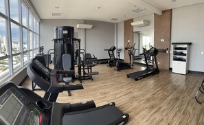 Un gimnasio con máquinas de cardio, equipo de pesas y una cinta de correr.