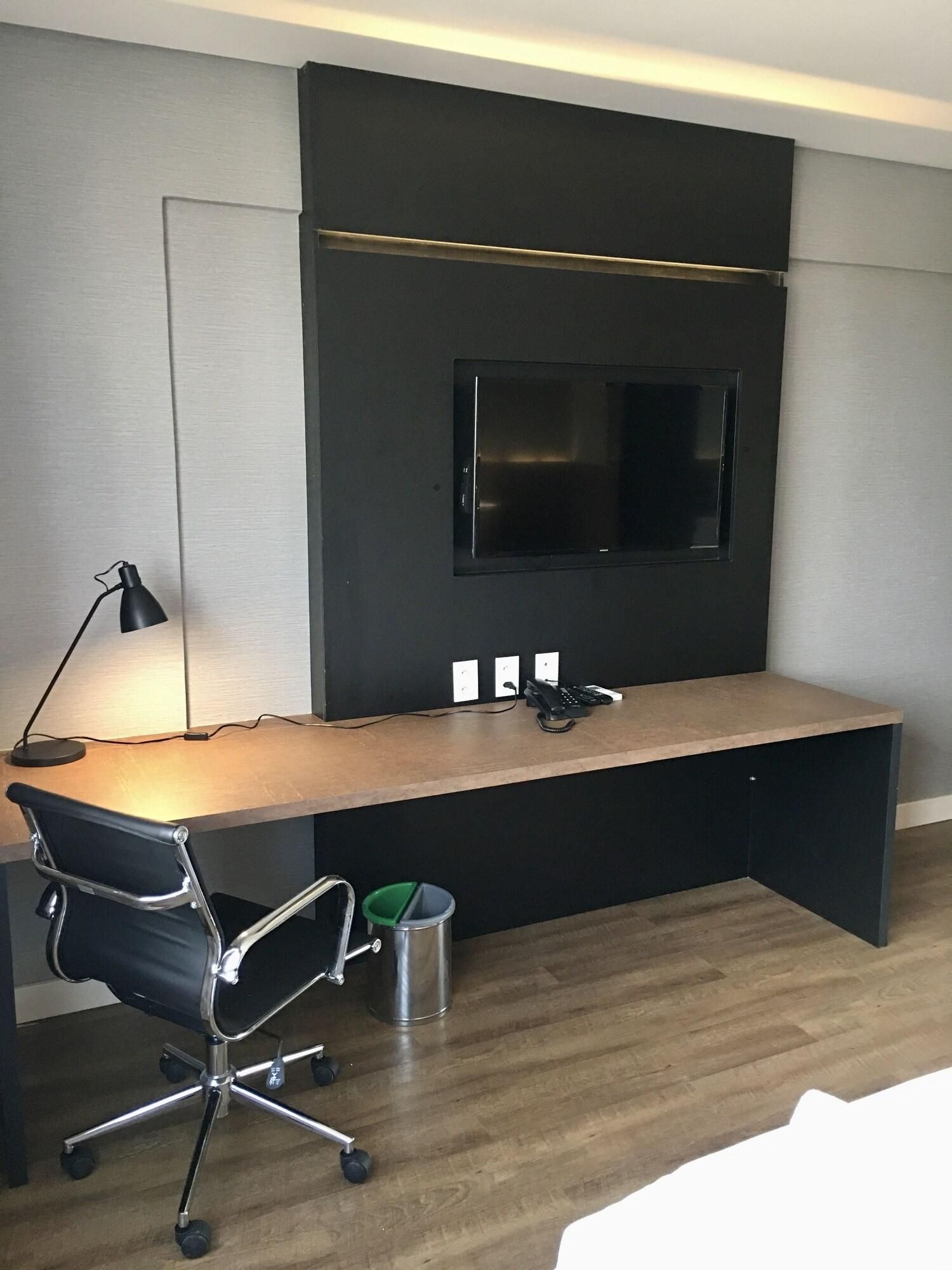 Un espacio de oficina moderno con escritorio, silla y televisor montado.