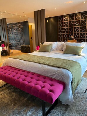 A modern hotel room with a large bed, a bench, and a decorative wall panel. - Qs Marista Stay And Hotel (Goiânia)
