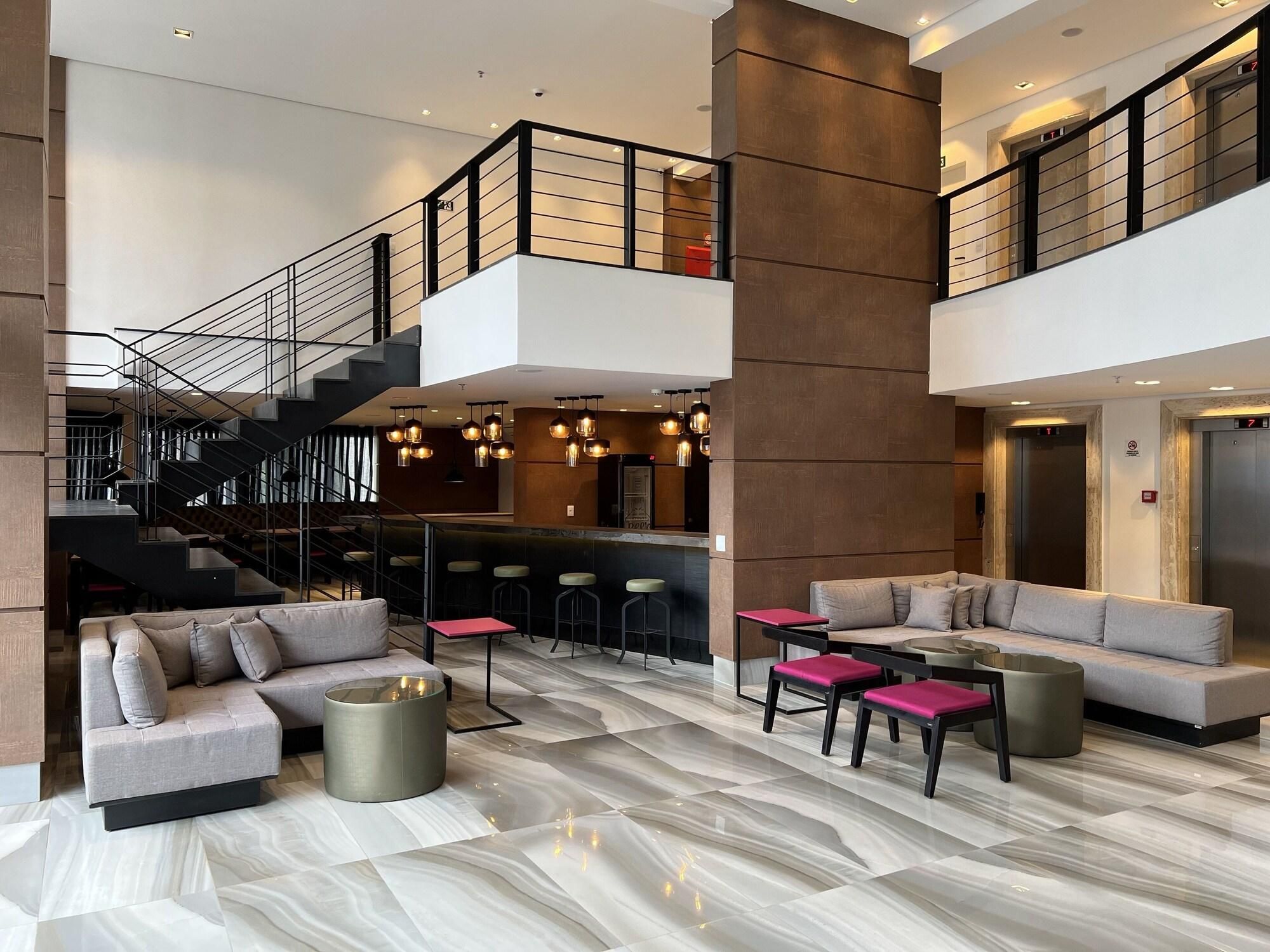 Un vestíbulo espacioso con una escalera moderna, zona de estar y un bar.