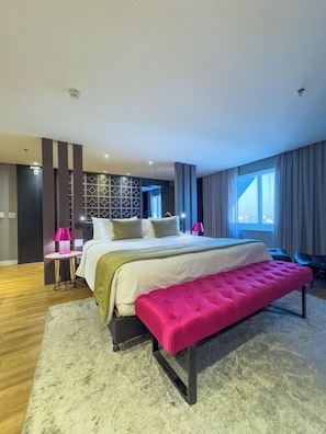 Ein modernes Schlafzimmer mit einem großen Bett, einer Bank, einem Schreibtisch und einer Wand mit Muster.
