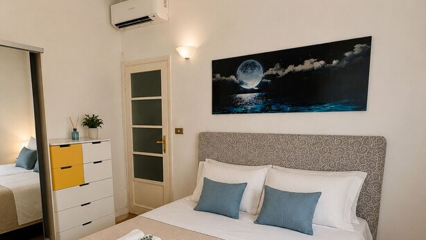 Una camera da letto con un letto, un quadro che raffigura il cielo notturno, un armadio e uno specchio.