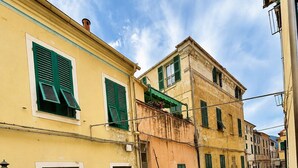 Una stretta via fiancheggiata da edifici con balconi e tende da sole, che suggerisce un'area pedonale.