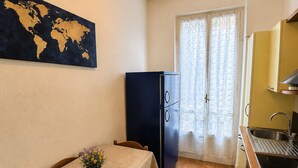 Una cucina compatta con un tavolo da pranzo, sedie, un frigorifero e un fornello.