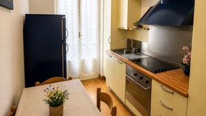 Una cucina compatta con frigorifero, fornello, forno e un tavolo da pranzo con sedie.