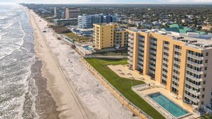 Un hotel costero con varias construcciones, una playa y una piscina.
