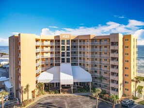 A multi-story hotel with a central atrium and balconies, located near a beach. - Oceanview Palace @ Oceania Beach Club (New Smyrna Beach)