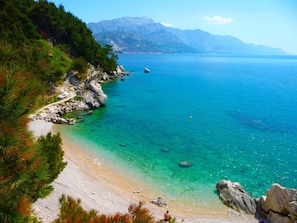 A coastal landscape with a clear turquoise sea, rocky shoreline, and a path leading to a beach. - Daria 4 by Interhome (Omiš)
