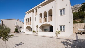 A modern two-story building with a flat roof, multiple balconies, and a stone wall in the background. - Daria 4 by Interhome (Omiš)