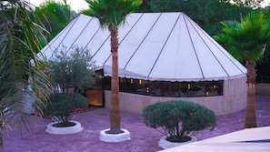 A building with a white, pyramid-like roof structure surrounded by palm trees and small bushes. - Weedan Ferme D'hôtes (Marrakech)