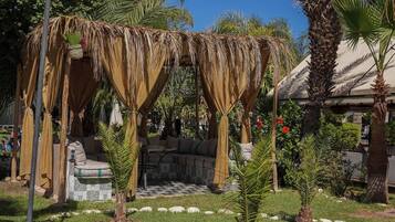 A garden with a thatched gazebo, a palm tree, and a solar panel.