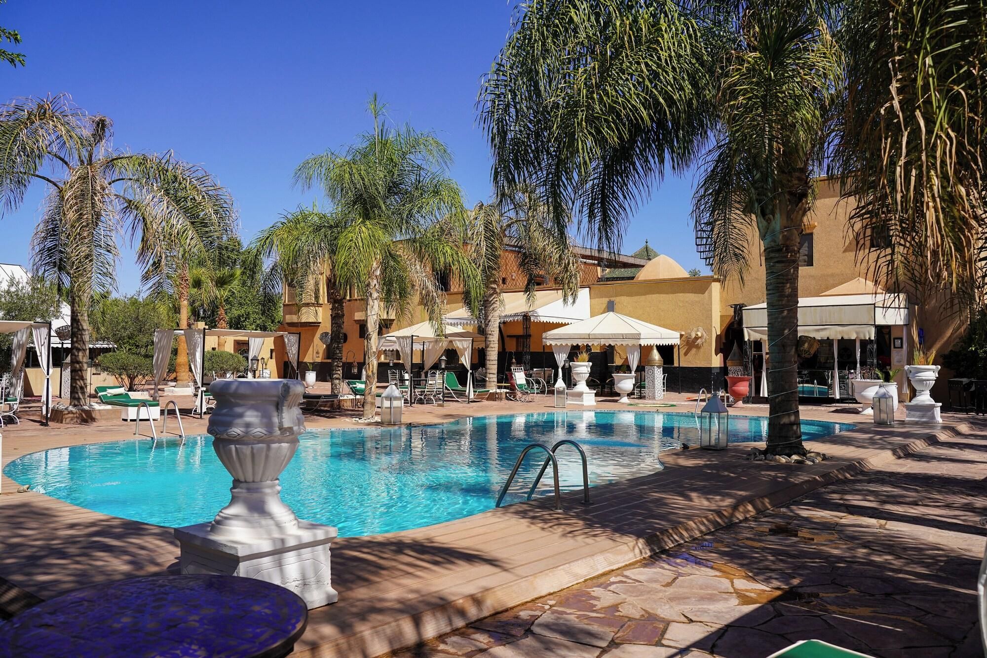 A pool area with lounge chairs, umbrellas, and palm trees.