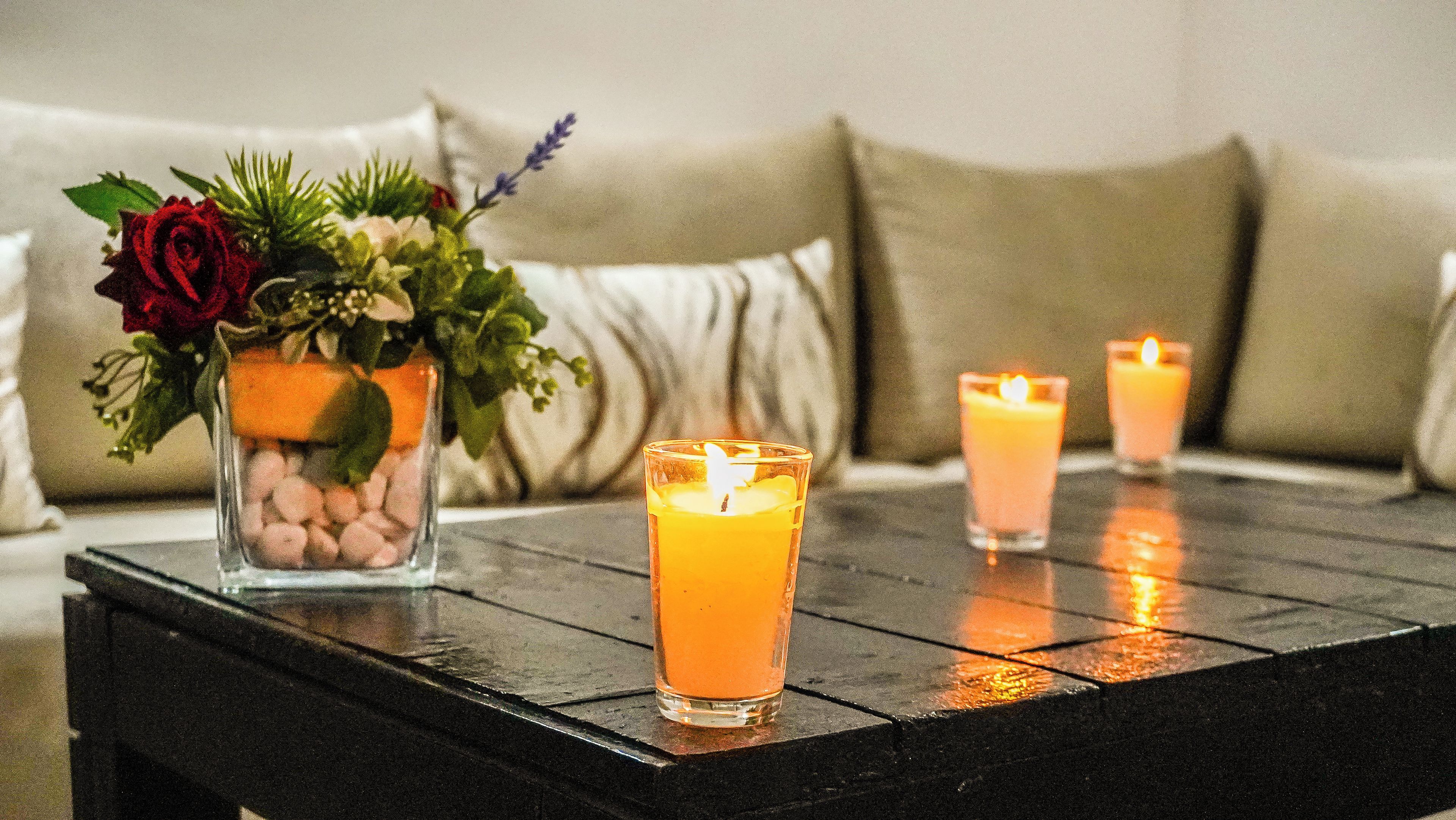 A table with three candles and a vase of flowers.