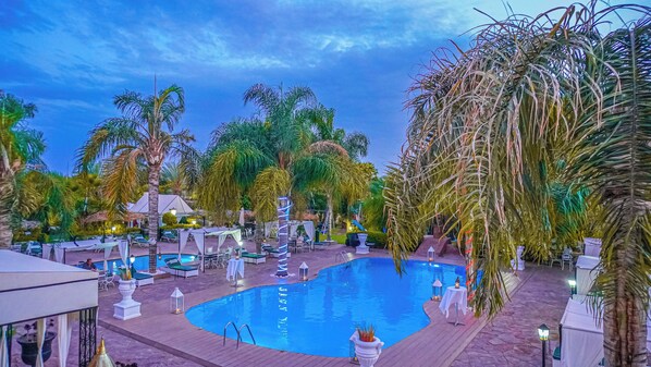 A pool area with lounge chairs and umbrellas, surrounded by palm trees. - Weedan Ferme D'hôtes (Marrakech)