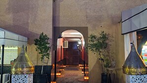 Ein Gebäudeeingang mit rotem Teppich, zwei weißen Zierpfeilern und einer Treppe.