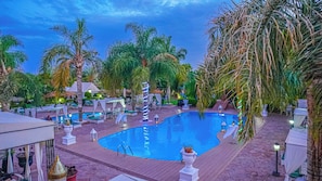 A pool area with lounge chairs and umbrellas, surrounded by palm trees and a clear sky. - Weedan Ferme D'hôtes (Marrakech)
