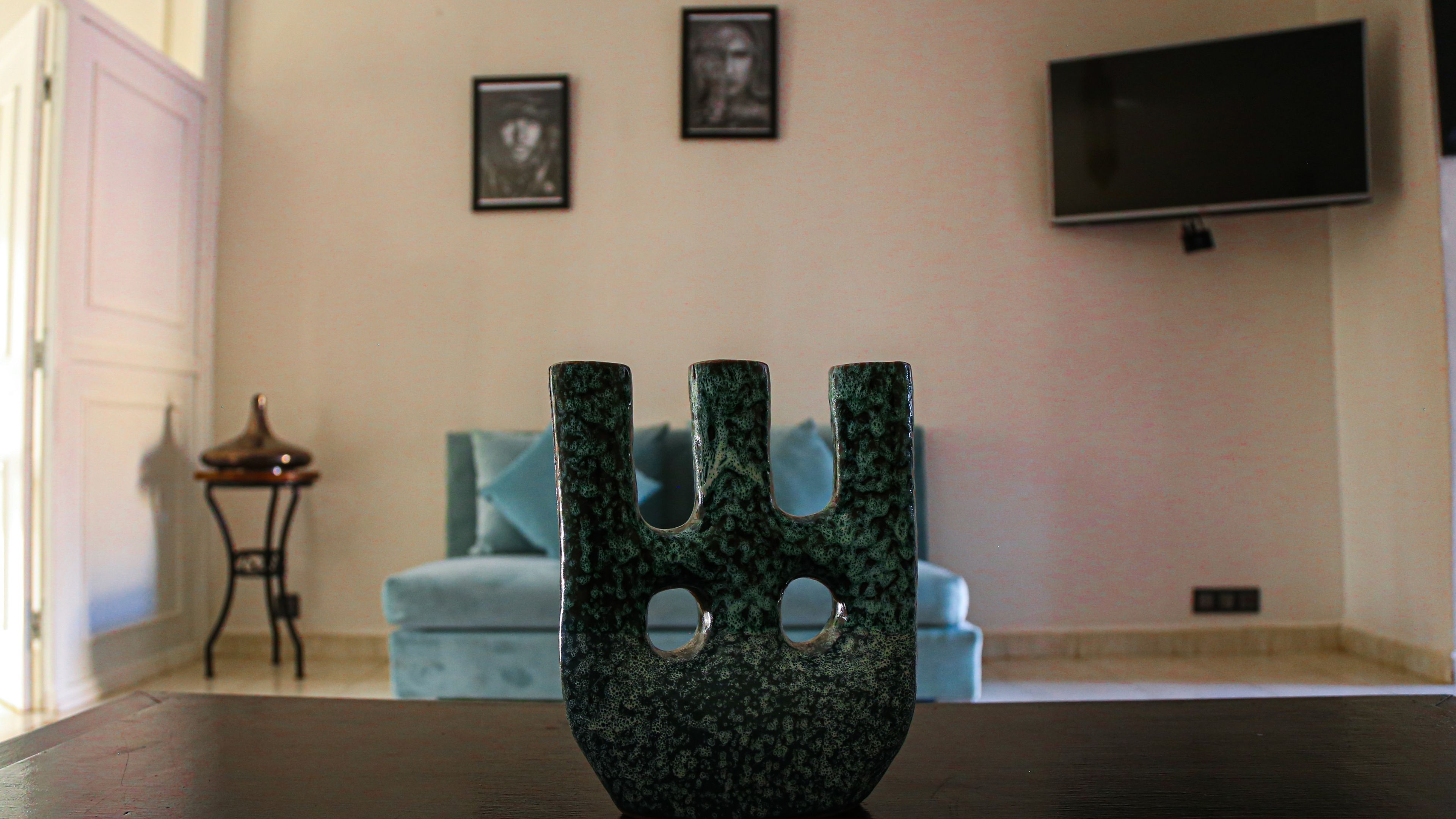 A room with a dark wooden table, a blue sofa, and a television mounted on the wall.