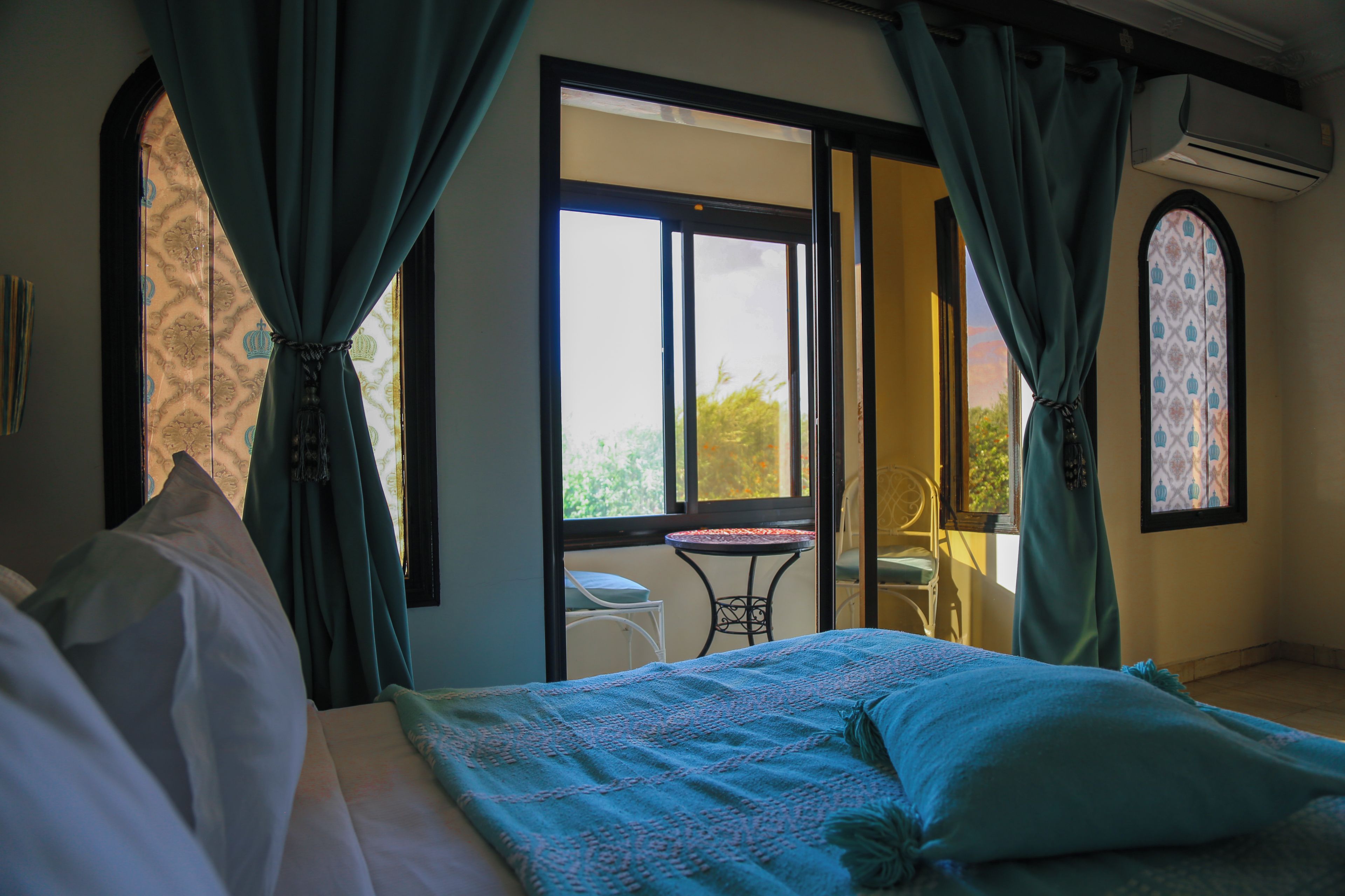 A bedroom with a bed, curtains, a window, and a view of the outdoors.