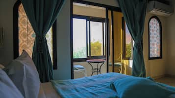 A bedroom with a bed, curtains, a window, and a view of the outdoors.