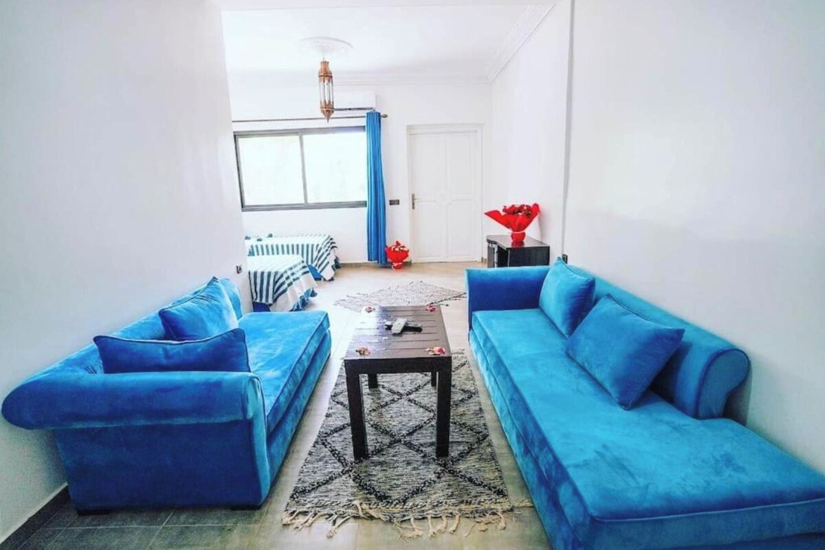 A living room with two blue sofas, a coffee table, and a rug.