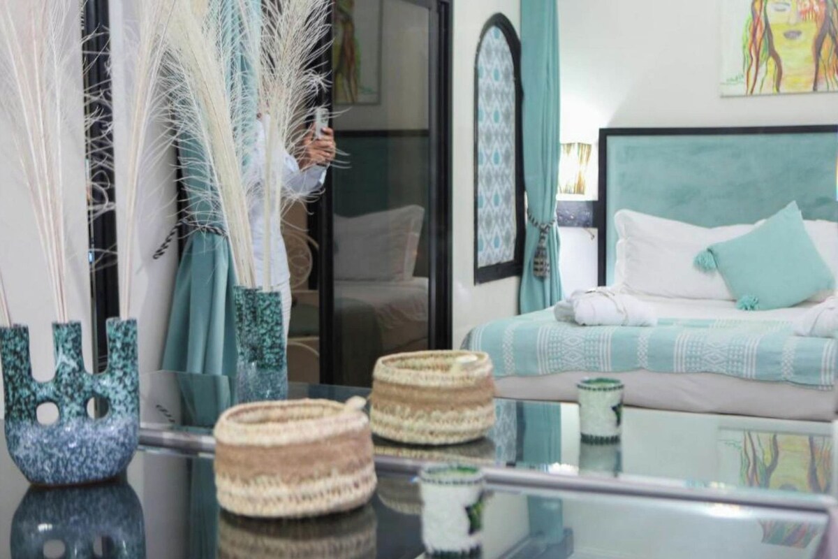 A room with a bed, a glass table with woven baskets, and decorative feathers.