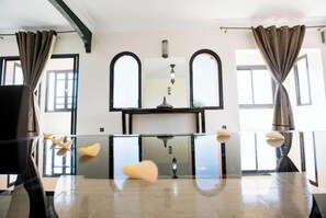 A room with a glass table, two arched windows, and a central light fixture. - Weedan Ferme D'hôtes (Marrakech)