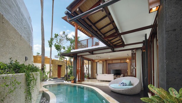 Ein moderner Poolbereich im Freien mit einem geschwungenen Design, einer überdachten Lounge und Blick auf die umliegende Landschaft.