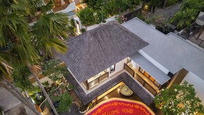 Luftaufnahme eines Hotels mit Dachterrasse, Innenbereich mit Sitzgelegenheiten und üppiger Bepflanzung.