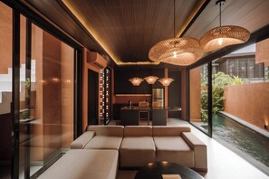 A modern interior with a seating area, a kitchen, and a view of a water feature. - Earth Villa Canggu By Ini Vie Hospitality (Payangan)