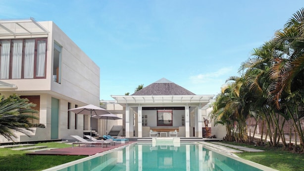 A modern pool area with a clear pool, lounge chairs, and umbrellas. - Nara Villa Canggu By Ini Vie Hospitality (Payangan)