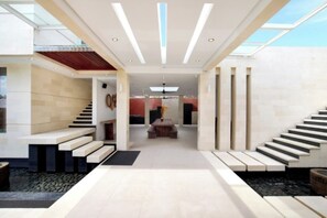 A modern interior with a central staircase, a seating area, and a view through a glass ceiling. - Nara Villa Canggu By Ini Vie Hospitality (Payangan)