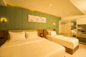 A hotel room with two beds, a green accent wall, and a painting of flamingos. - Hotel Harriet (Rameshwaram)
