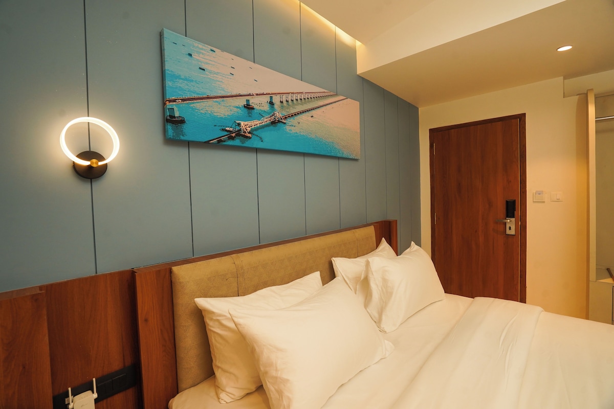 A hotel room with a bed, a wall-mounted artwork of a pier, and a wooden headboard.