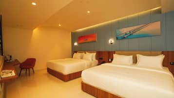 A hotel room with two beds, a desk, a chair, and a painting on the wall.