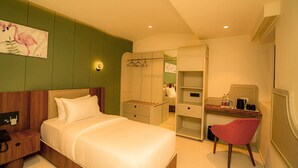 Une chambre d’hôtel avec un lit, un bureau et une chaise, une armoire et un tableau au mur.