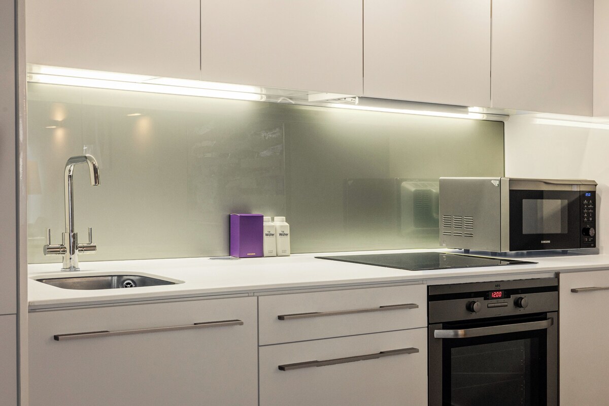 A modern kitchen with stainless steel appliances, a double sink, and a built-in oven.