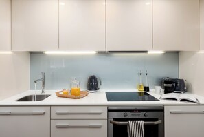 A modern kitchen with a stainless steel sink, a coffee maker, a kettle, and a toaster. - Liverpool Street - Your Apartment (London)