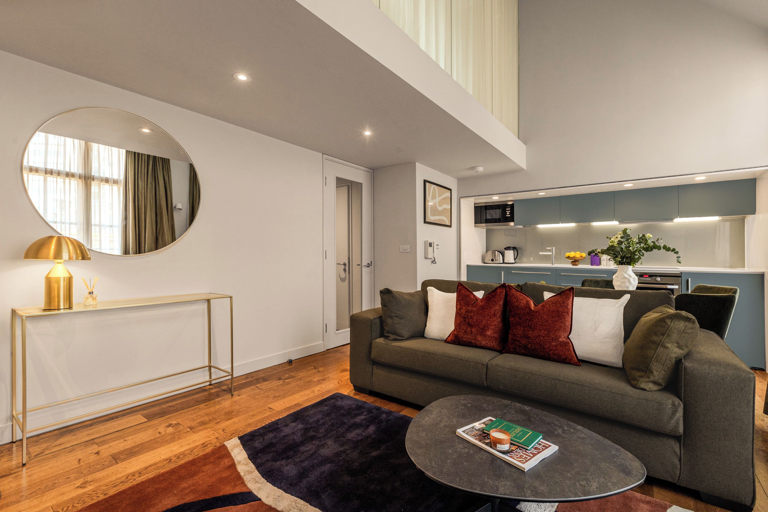 A modern living room with a sofa, coffee table, and a round mirror.