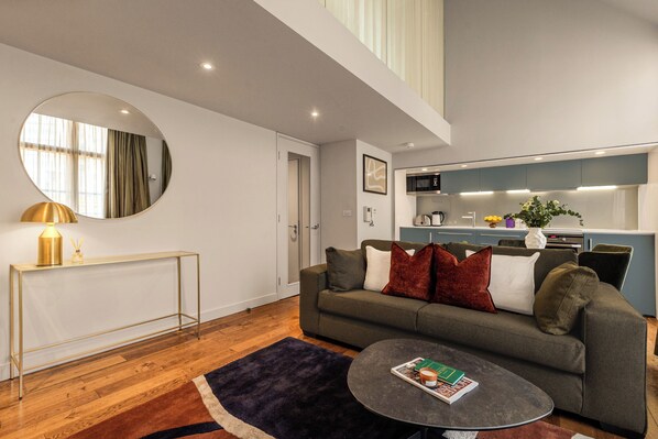 A modern living room with a sofa, coffee table, and a round mirror. - Liverpool Street - Your Apartment (London)