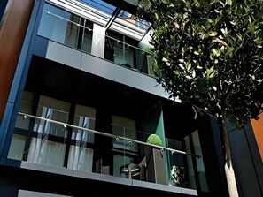 A modern building with a balcony, large windows, and a tree in front. - Liverpool Street - Your Apartment (London)