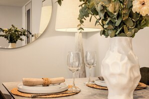 A dining table with a white vase, two wine glasses, and a rolled napkin. - Liverpool Street - Your Apartment (London)