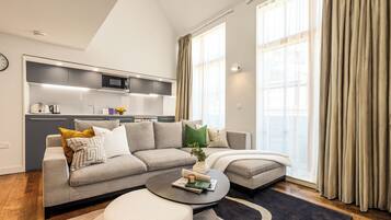 A modern living room with a grey sofa, a coffee table, and a kitchen in the background.
