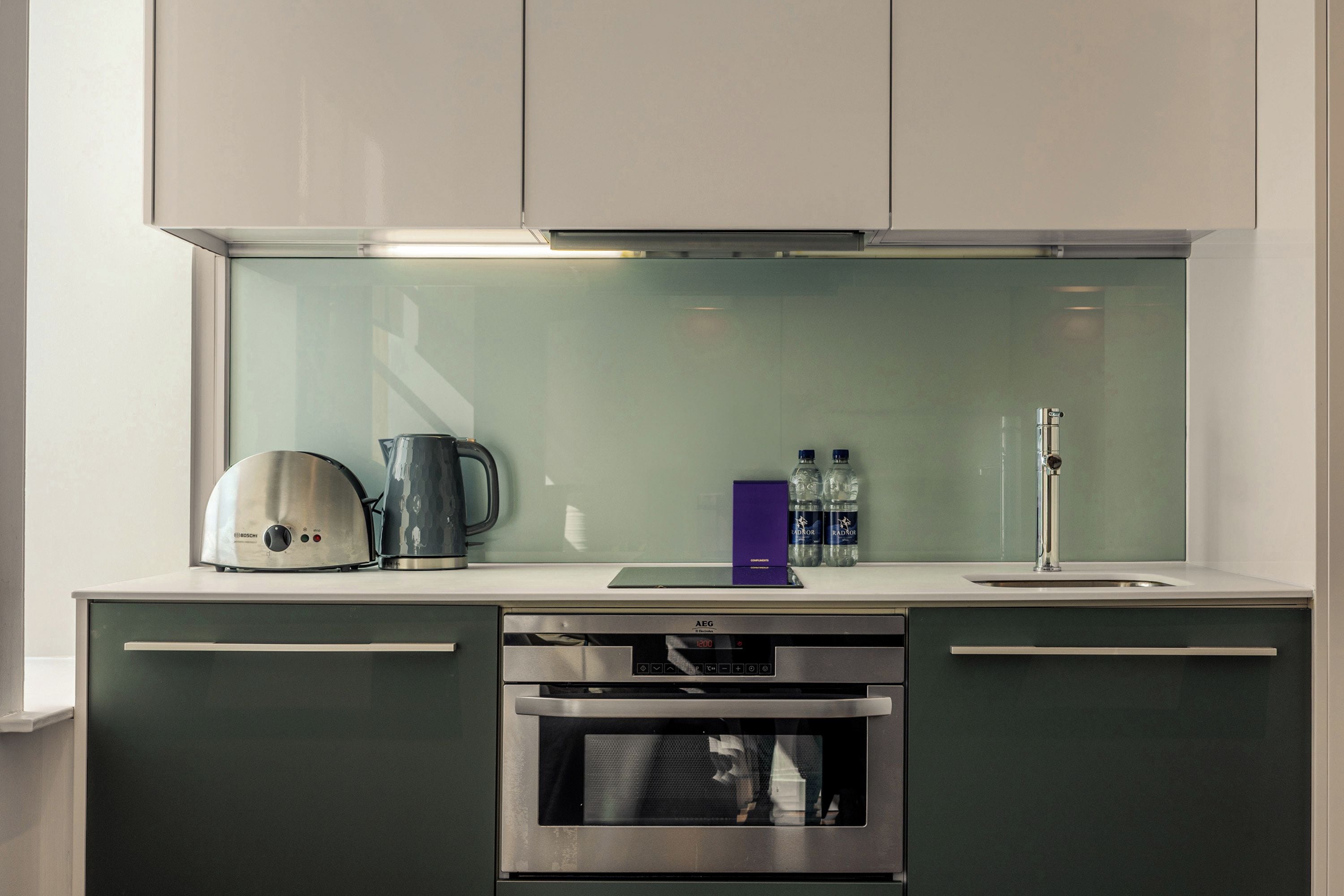 Una cocina moderna con horno empotrado, cafetera y dispensador de agua.