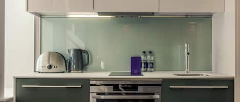 A modern kitchen with a built-in oven, a coffee maker, and a water dispenser.