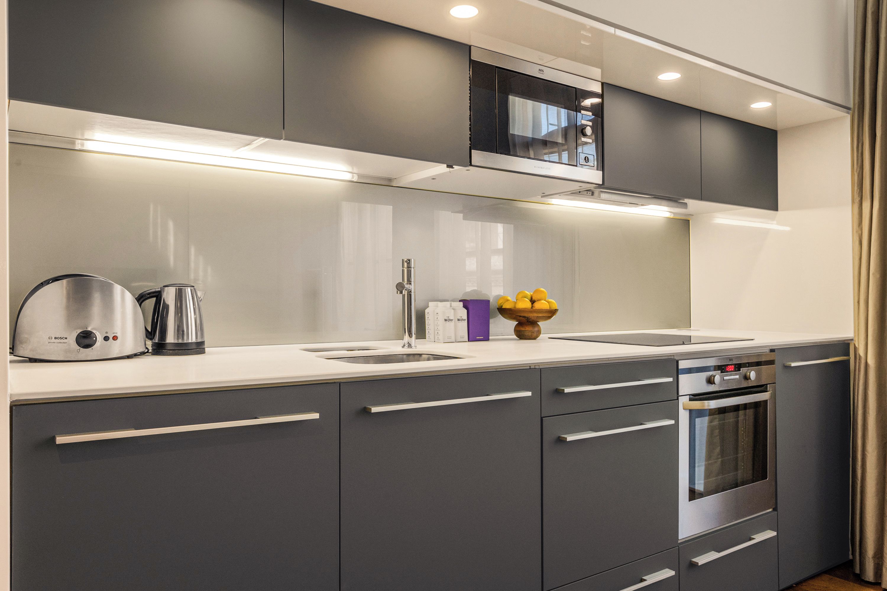 Una cucina moderna con mobili grigi, elettrodomestici in acciaio inossidabile e forno integrato.