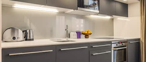 Una cocina moderna con gabinetes grises, electrodomésticos de acero inoxidable y un horno empotrado.