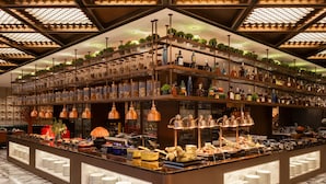A bar area with multiple shelves of bottles and a buffet counter with plates and food items. - Grand Skylight International Hotel Jinan (Jinan)