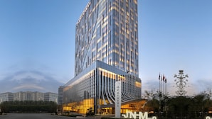 A modern high-rise hotel with a reflective glass facade, multiple floors, and a prominent entrance with signage. - Grand Skylight International Hotel Jinan (Jinan)